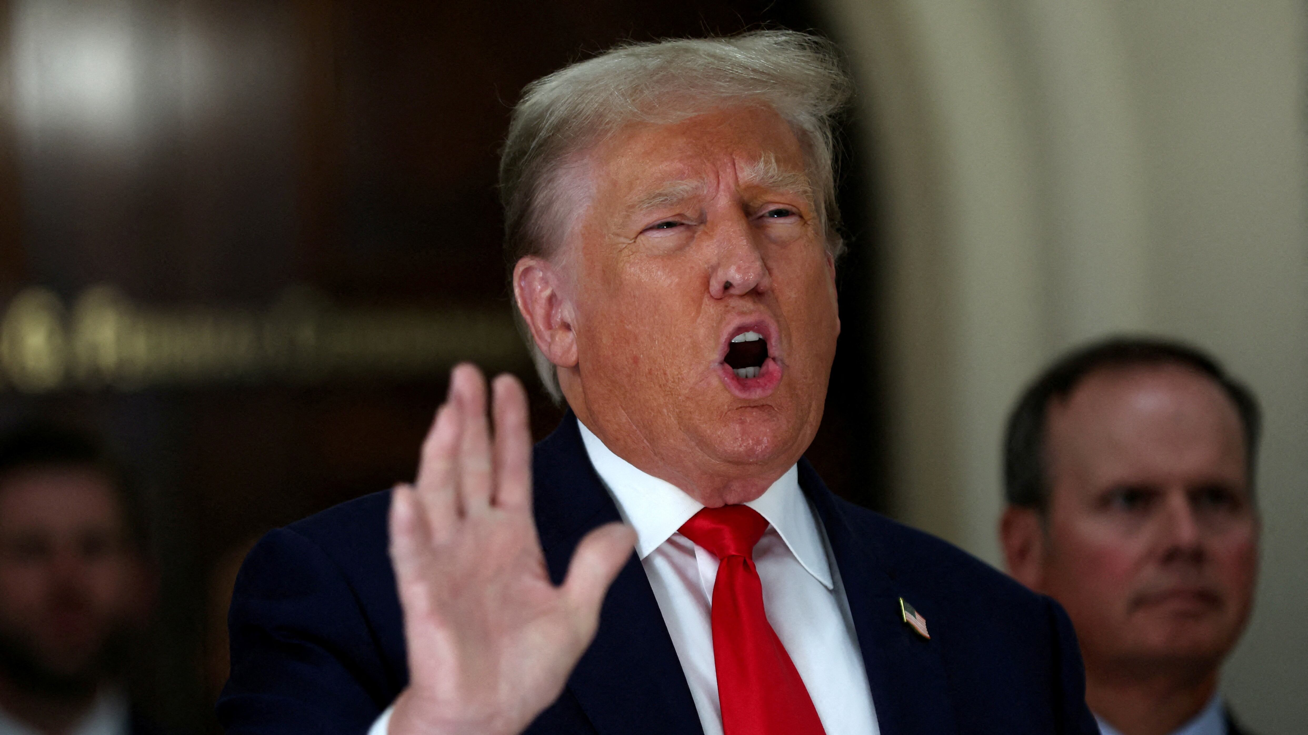 Former U.S. President Donald Trump gestures while talking to the media during a break as he attends trial in a civil fraud case