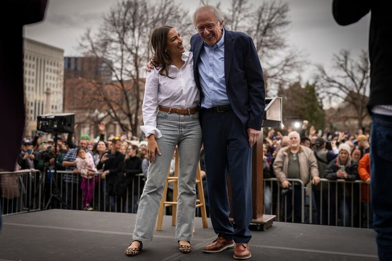 U.S. Rep. Alexandria Ocasio Cortez (D-NY) and Senator Bernie Sanders (I-VT) share a moment onstage during a rally on March 21, 2025 at Civic Center Park in Denver, Colorado.