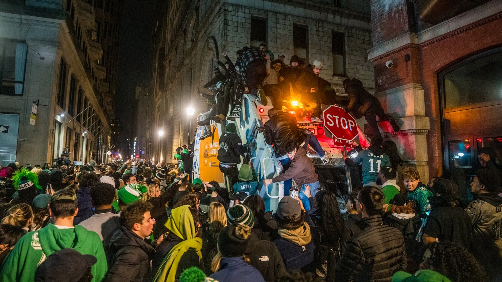Philadelphia Eagles fans swarm a dump truck while celebrating their team's Super Bowl victory.