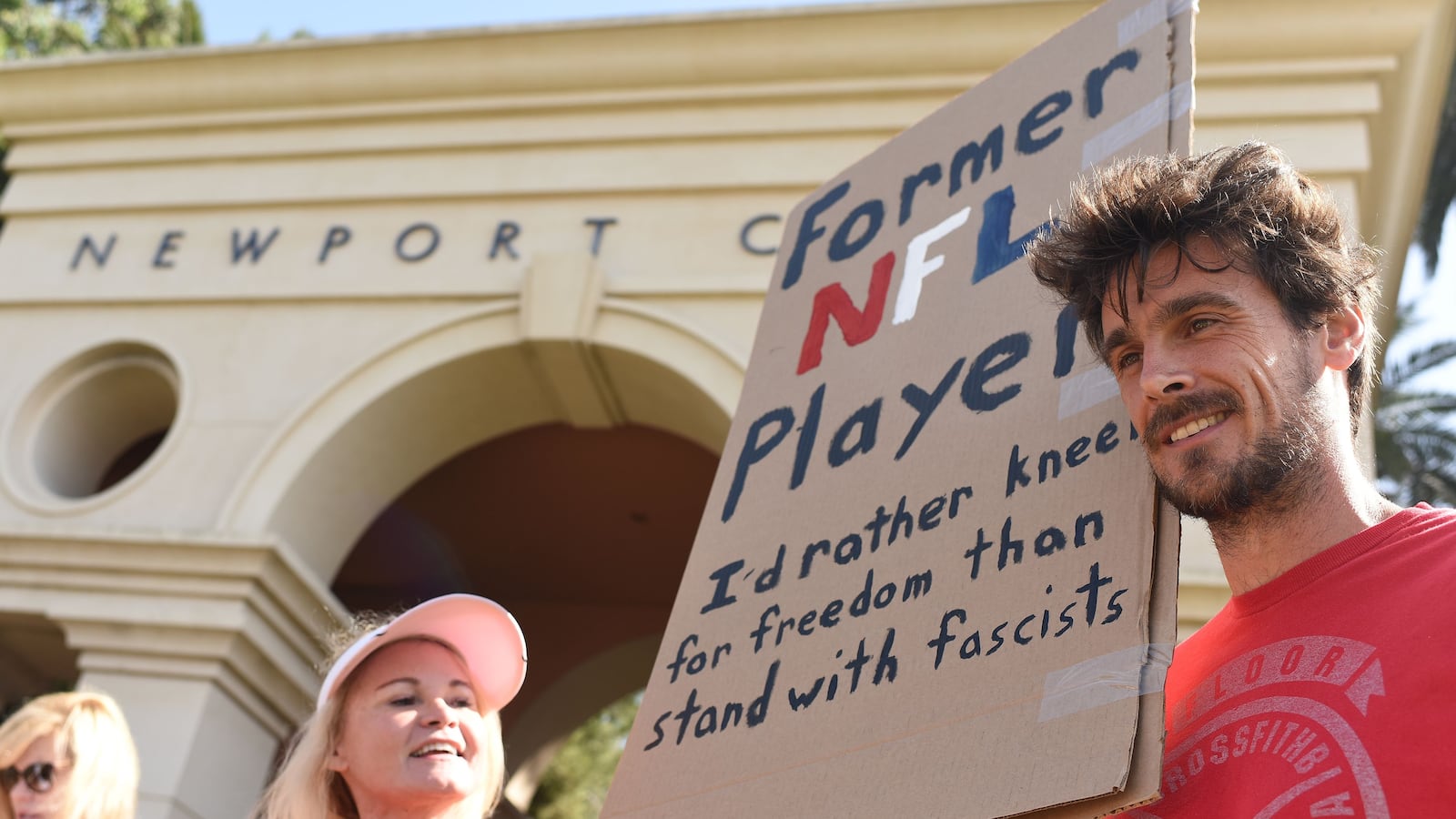 Former Minnesota Vikings NFL player Chris Kluwe holds a sign at a protest in 2017 that says, "Former NFL Player. I'd rather kneel for freedom than stand with fascists."
