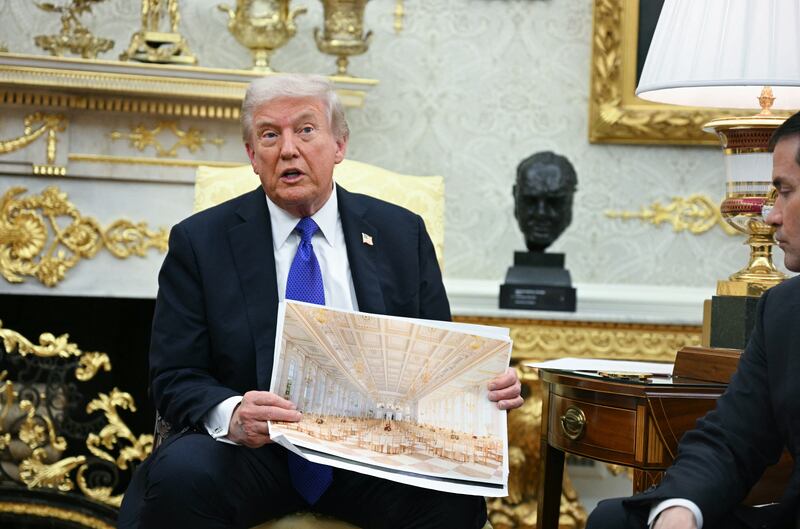 President Donald Trump, sitting in his heavily gilded Oval Office, shows of a rendering of his $300 million ballroom.(Photo by Jim WATSON / AFP) (Photo by JIM WATSON/AFP via Getty Images)