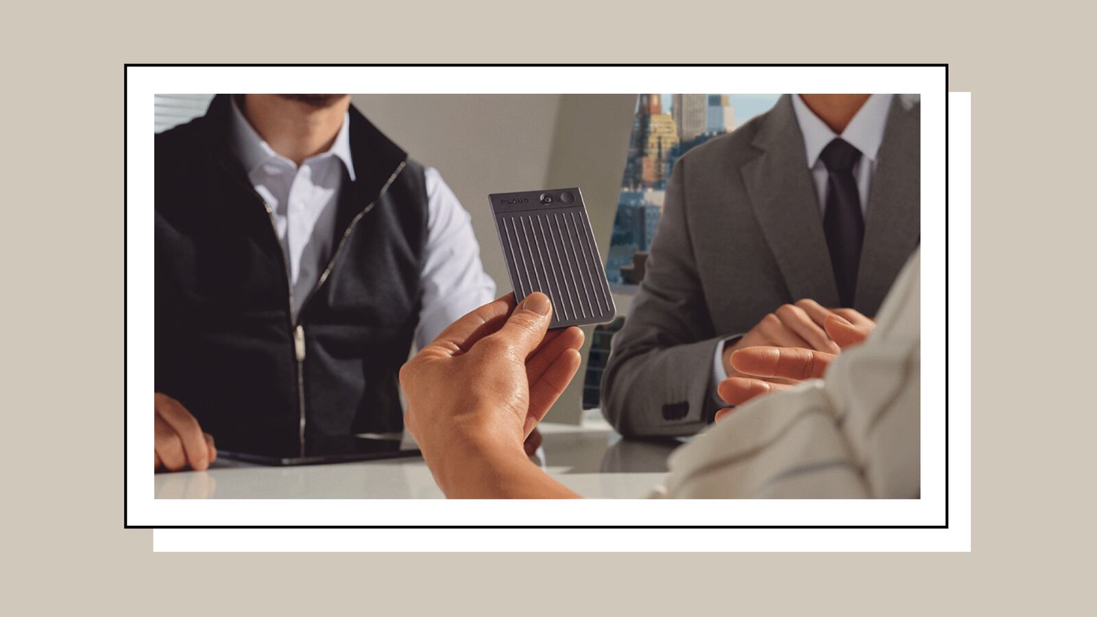 A group of three business men having a meeting. They are dressed professionally and one is holding the PLAUD.AI NOTETAKER.