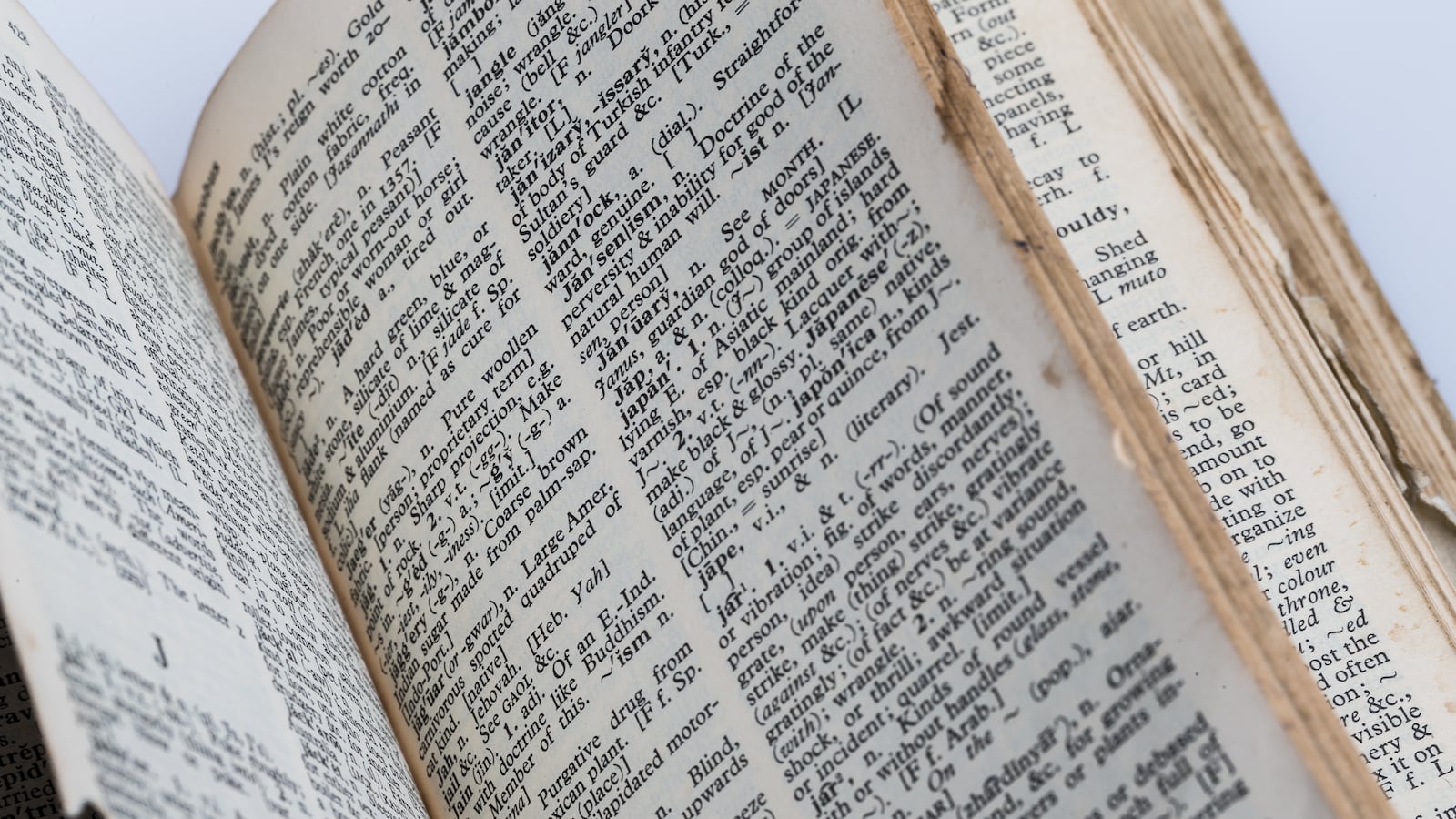 A very old dictionary with torn pages against white background.