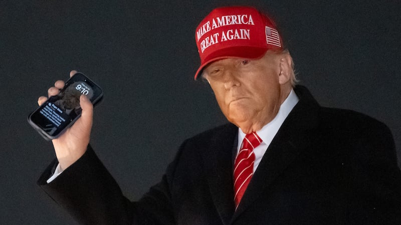 US President Donald Trump disembarks from Air Force One while holding his cellphone at Joint Base Andrews in Maryland, May 30, 2025.