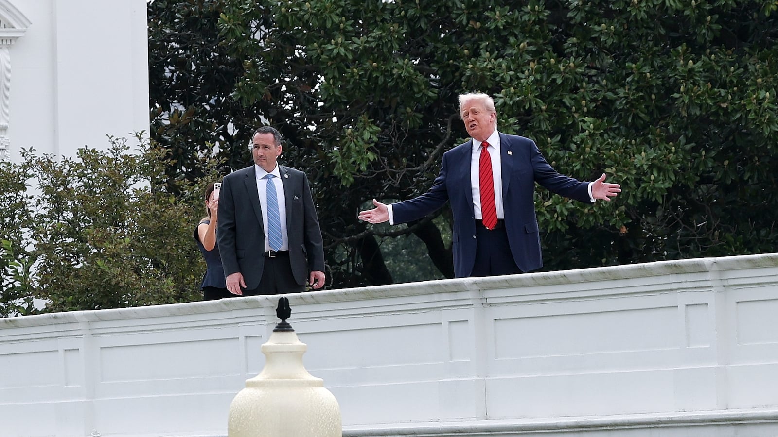 U.S. President Donald Trump gestures while answering questions from reporters as he tours the roof of the West Wing of the White House