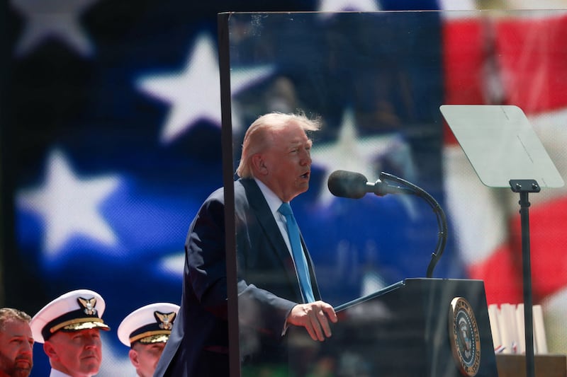 President Donald Trump stands behind protective glass as he delivers a commencement address at the U.S. Coast Guard Academy in New London, Connecticut, on May 20, 2026.