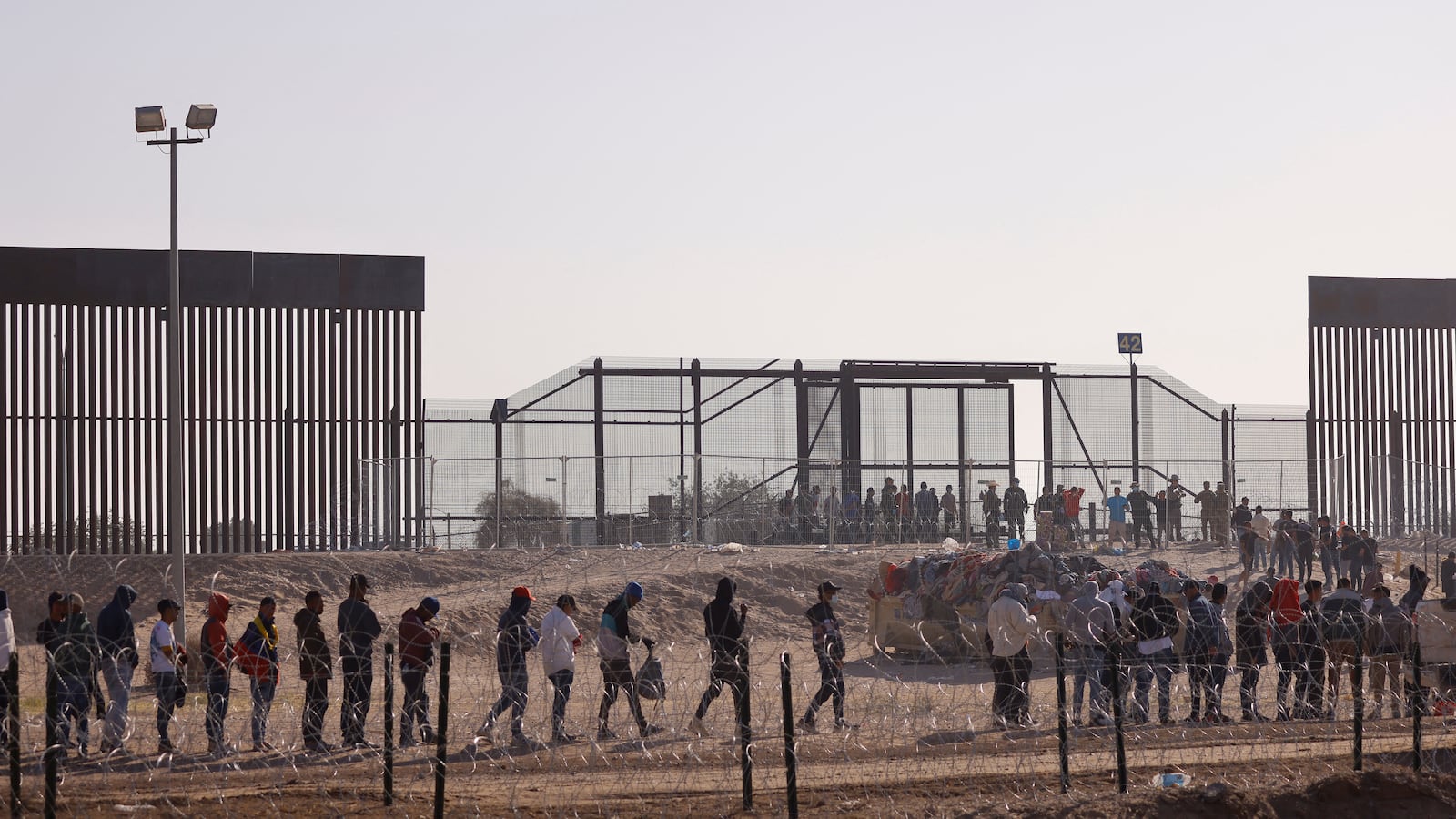 Migrants stand near the border wall after having crossed the U.S.-Mexico border to turn themselves in to U.S. Border Patrol agents.