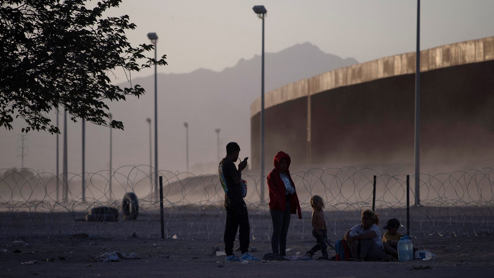 Migrants sit in a dusty field as they wait to be picked up by U.S. Customs and Border Protection officers near the U.S. border wall near El Paso, Texas, May 10, 2023.