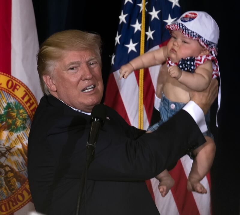 President Donald Trump holds a baby during a campaign rally before his first term.