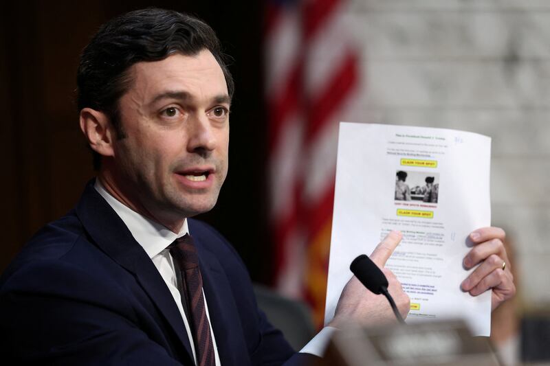 U.S. Senator Jon Ossoff (D-GA) holds a printout of a fundraising email from President Donald Trump's political action committee, which uses an image from a dignified transfer honoring six fallen U.S. soldiers and promises access to the president’s "private national security briefings", during a Senate Intelligence Committee hearing on Capitol Hill in Washington, D.C., U.S., March 18, 2026.