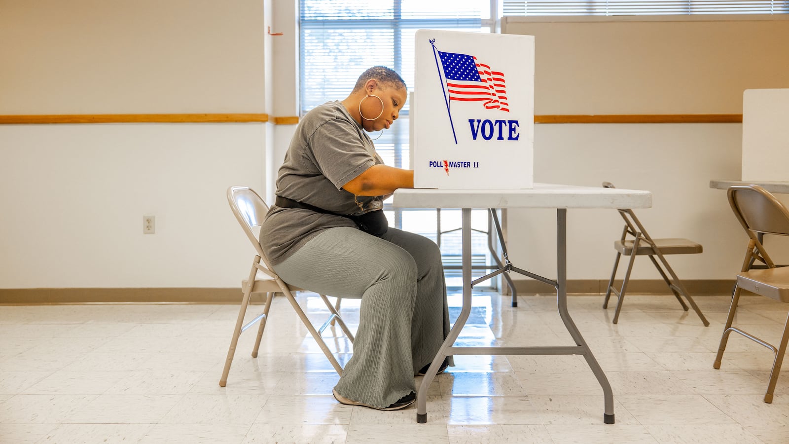 A woman seated at a polling station votes