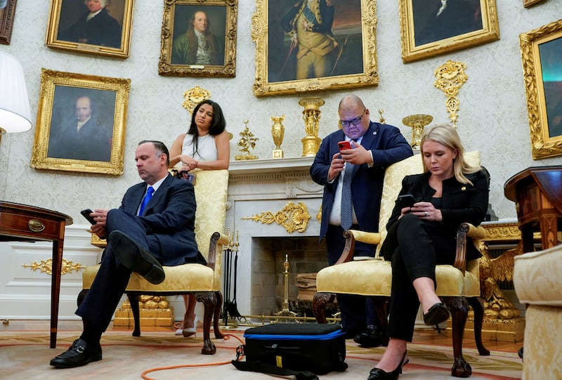 Katie Miller, White House Press Secretary Karoline Leavitt, White House Deputy Chief of Staff Dan Scavino and White House Communications Director Stephen Cheung look at their smartphones during a press conference with President Donald Trump and Elon Musk, in the Oval Office at the White House in Washington, D.C., on May 30, 2025.