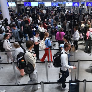 Travelers move through a TSA security screening line at Orlando International Airport on the day before Thanksgiving in Orlando, Florida, United States, on November 26, 2025.