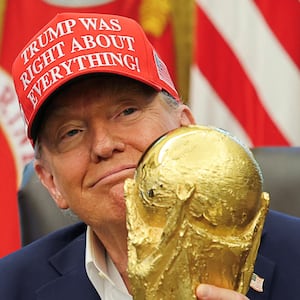 U.S. President Donald Trump wears a 'Trump Was Right About Everything!' hat while holding the FIFA World Cup Trophy, as he makes an announcement on the 2026 FIFA World Cup, in the Oval Office at the White House in Washington, D.C., U.S., August 22, 2025. REUTERS/Jonathan Ernst