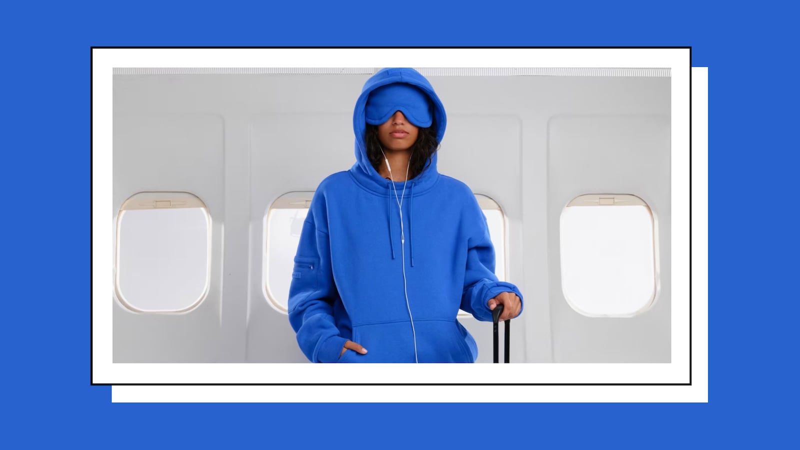 Model wearing a blue Airplane Mode Travel Hoodie by Comfrt in front of airplane windows