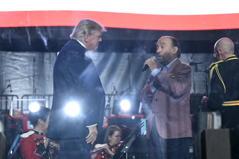 President Donald Trump (L) listens as singer Lee Greenwood performs during the kick-off celebration for the "Great American State Fair" on the National Mall in Washington, DC, June 24, 2026.