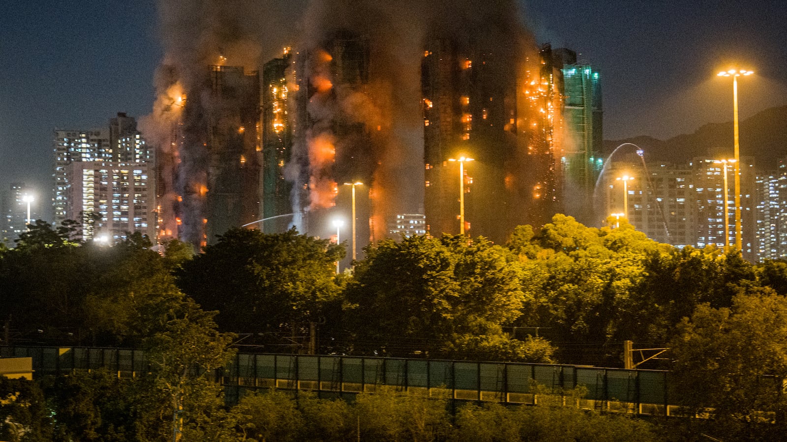 Thick smoke and flames rise as a major fire engulfs several apartment blocks at the Wang Fuk Court residential estate in Hong Kong's Tai Po district on November 26, 2025. At least four people were killed when a fire engulfed several high-rise blocks in a Hong Kong residential estate on November 26, the government said, with media reporting that some residents were trapped inside. (Photo by AFP via Getty Images)