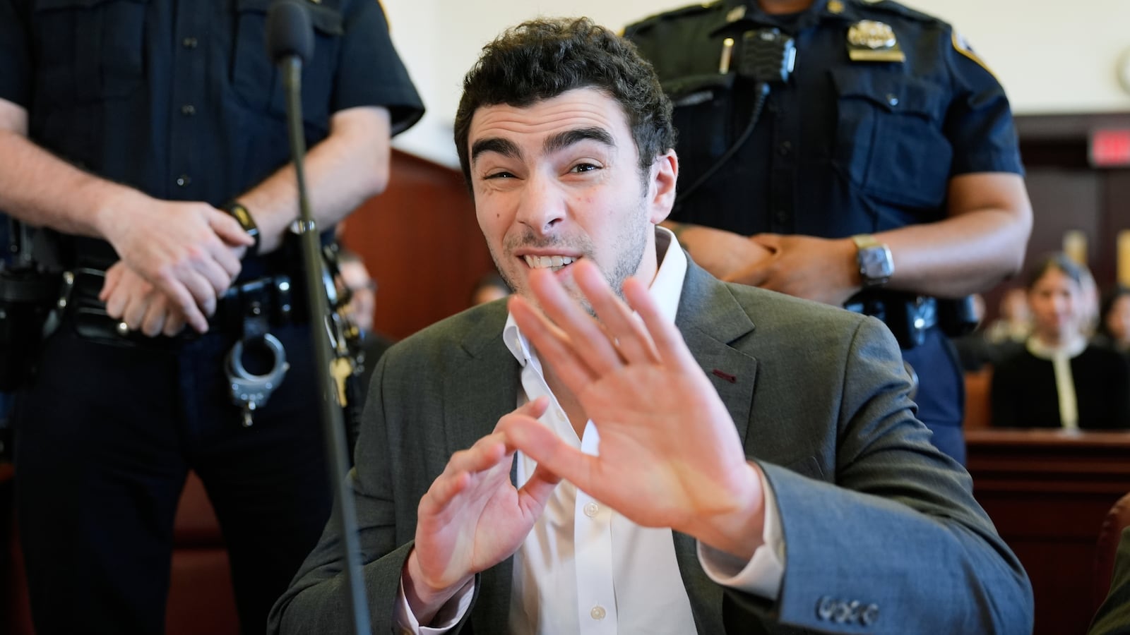 NEW YORK, NEW YORK - DECEMBER 16: Luigi Mangione talks to a photographer as he appears for a suppression of evidence hearing in the killing of UnitedHealthcare CEO Brian Thompson in Manhattan Criminal Court on December 16, 2025 in New York City. Mangione's lawyers will argue to have the evidence thrown out because police officers allegedly did not read Mangione his Miranda rights and did not have a proper warrant when they searched his backpack at a Pennsylvania McDonald's last December. He is accused of fatally shooting UnitedHealthcare CEO Brian Thompson and faces state and federal murder charges. (Photo by Seth Wenig-Pool/Getty Images)