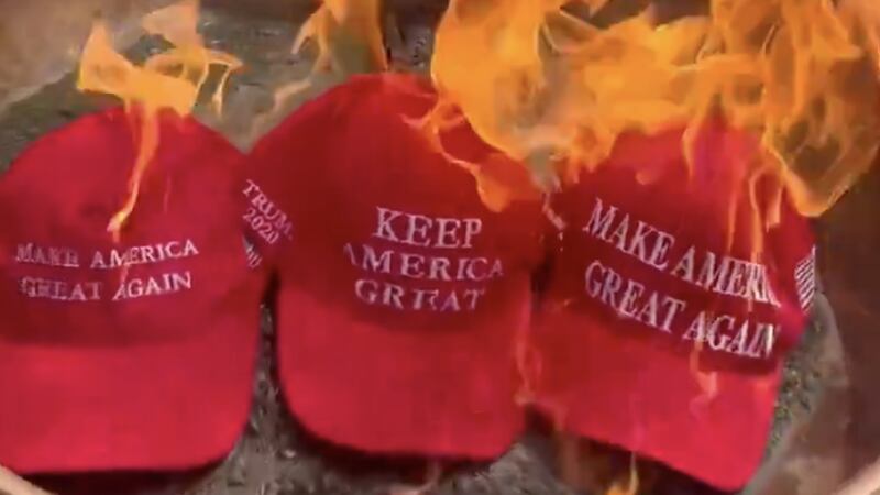 A screenshot from a video of a Trump supporter burning their MAGA hat.