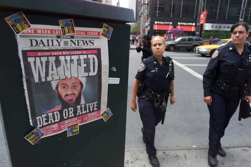 Police officers pass a Daily News cover showing a picture of Osama Bin Laden, who's been called the prime suspect in the terrorist attack on the World Trade Center. The headline reads: Wanted Dead or Alive.