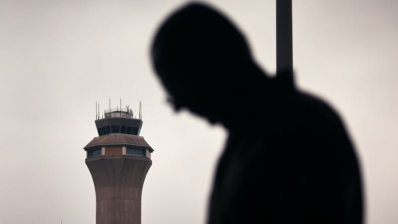 A man stands outside Terminal C with the airport control tower in the background at Newark Liberty International Airport.