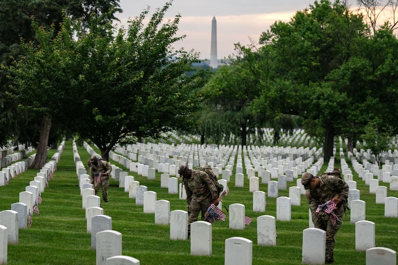 ARLINGTON, VIRGINIA - MAY 23: Members of the 3rd U.S. Infantry Regiment, also known as the "Old Guard," place flags at the headstones of U.S. military personnel buried at Arlington National Cemetery ahead of Memorial Day, on May 23, 2024 in Arlington, Virginia.