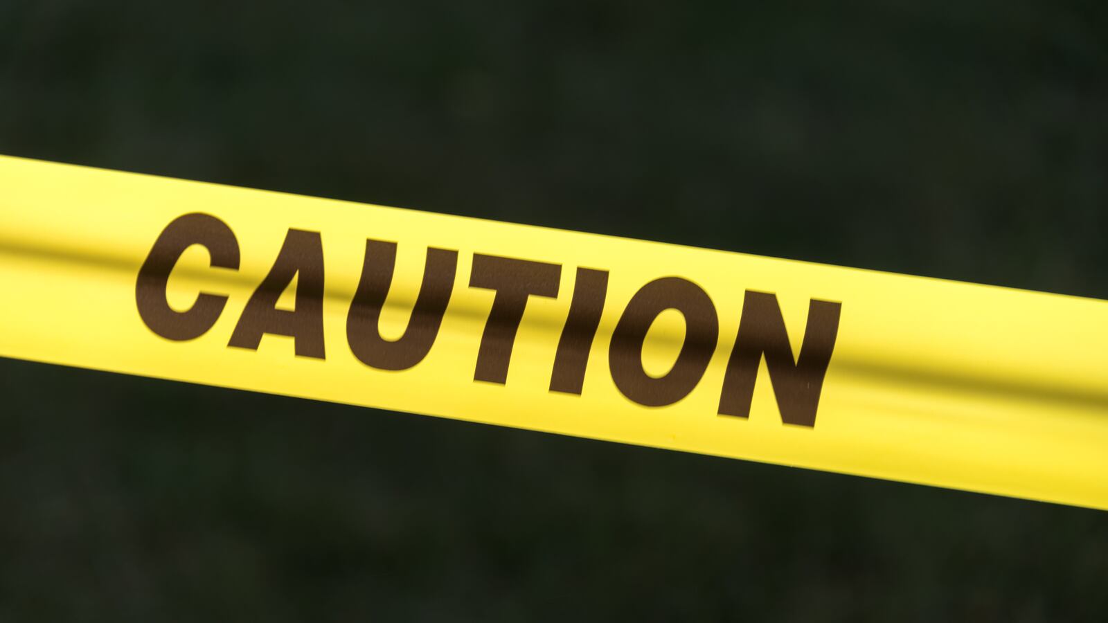 Caution sign tape against black background concept of warning and danger.