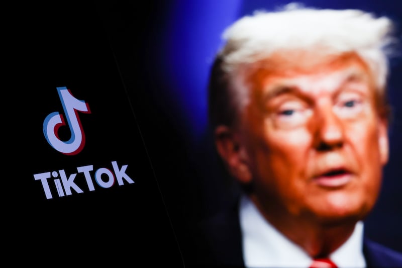 TikTok logo displayed on a phone screen and photo of Donald Trump taken on June 25 in The Hague displayed on a laptop screen in the background are seen in this illustration photo taken in Poland on July 21, 2025.