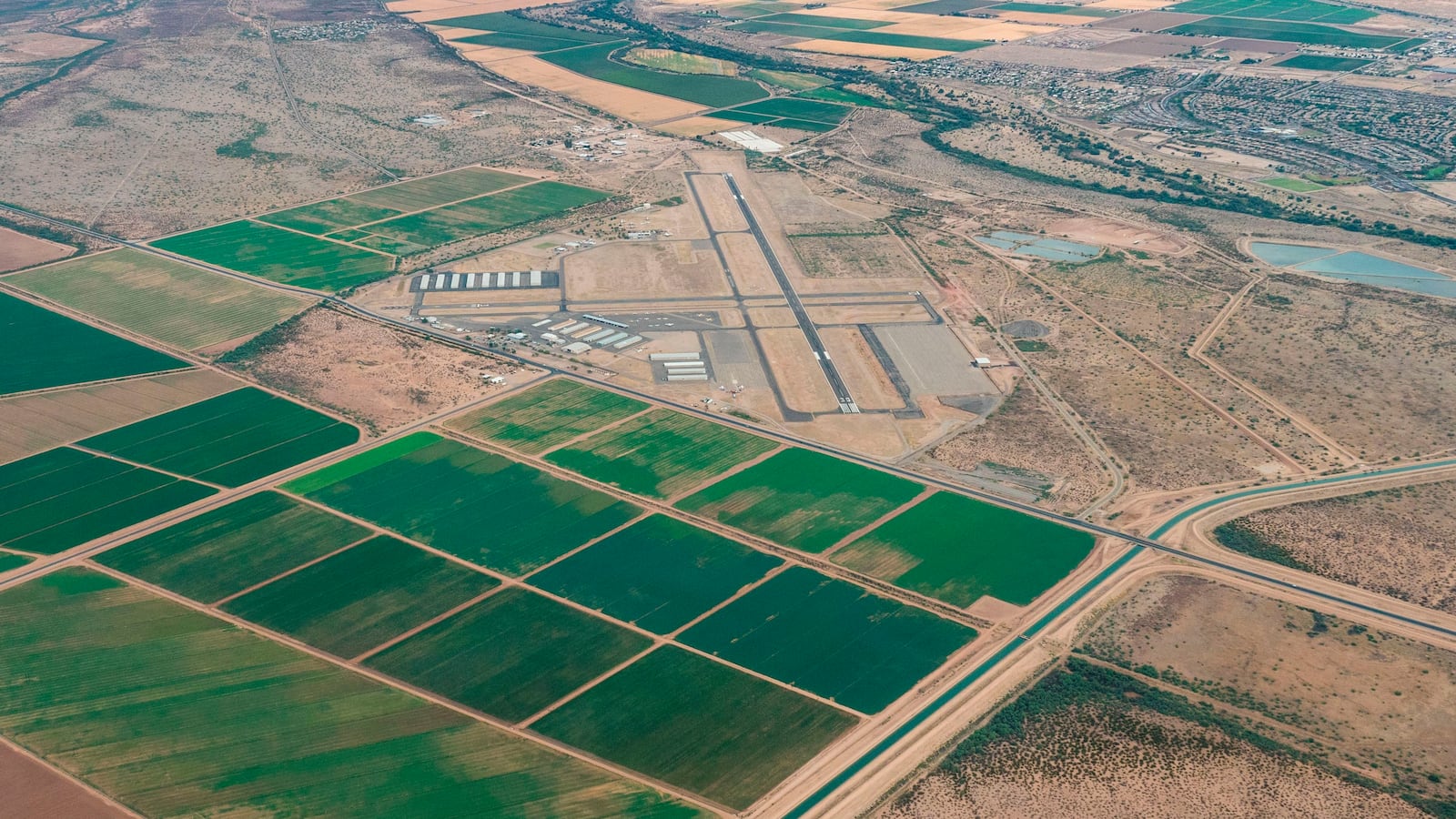 Aerial view of farmlands in Avra Valley south of Avra Valley Rd. and the Central Arizona Project, CAP, canal with Marana Regional Airport in the background.