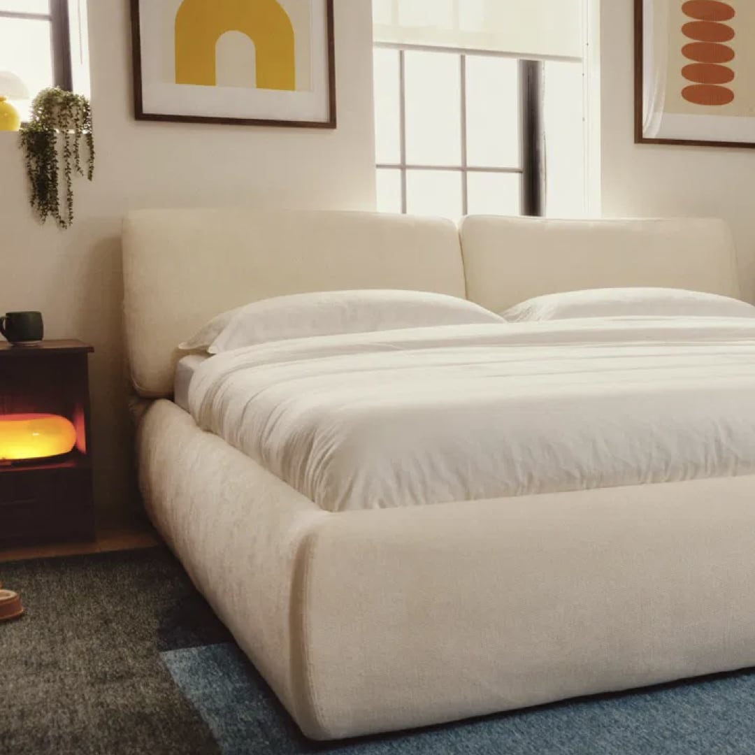 Cozey Ara Bed System styled in a modern bedroom with upholstered bed frame, neutral fabric finish, white bedding, and minimalist decor