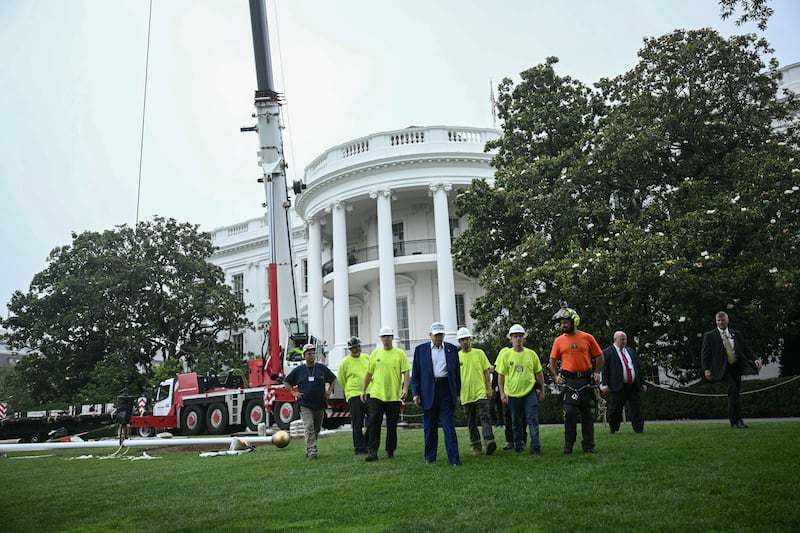 US President Donald Trump walks toward the press to speak as workers install a large flag pole on the South Lawn of the White House in Washington, DC on June 18, 2025.
