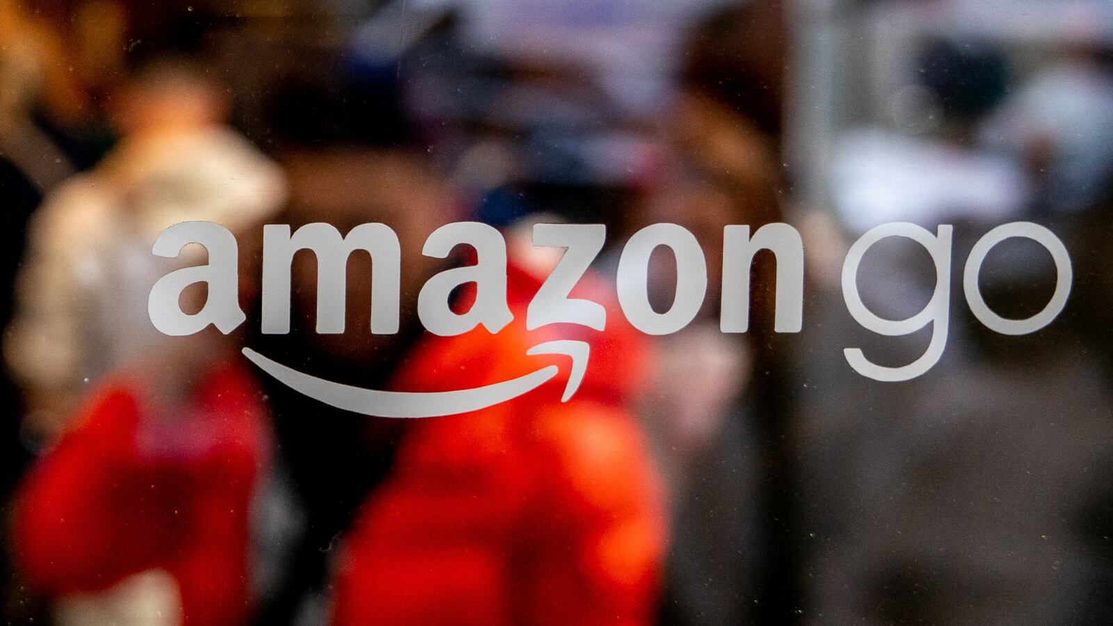 An Amazon Go logo on a convenience store with people blurred in the back