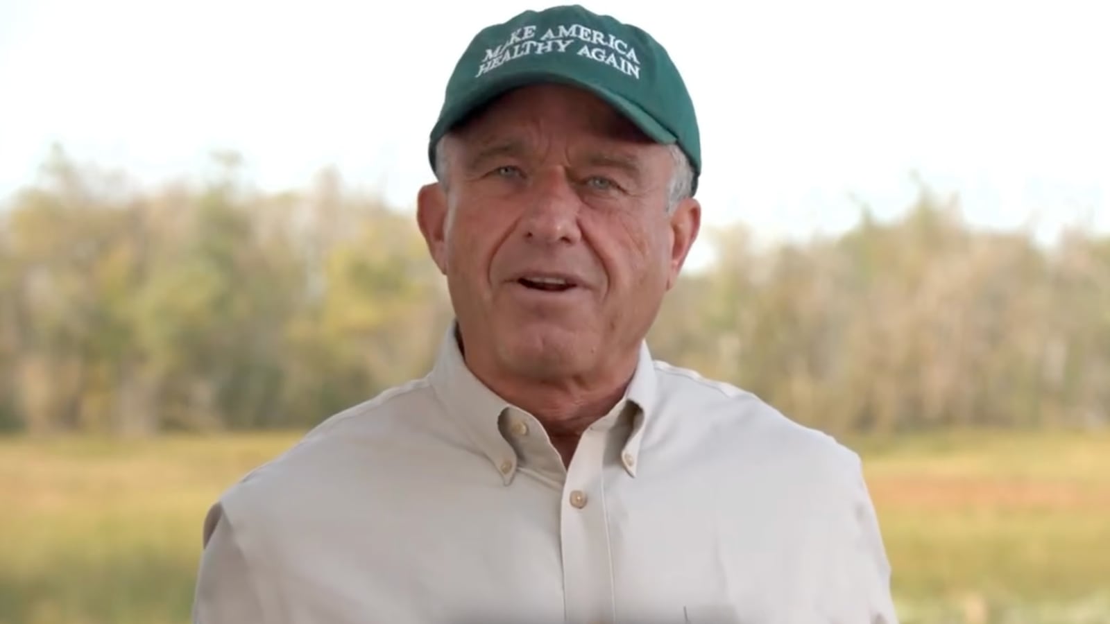Robert F. Kennedy Jr. stands in a field wearing a Make America Healthy Again hat.