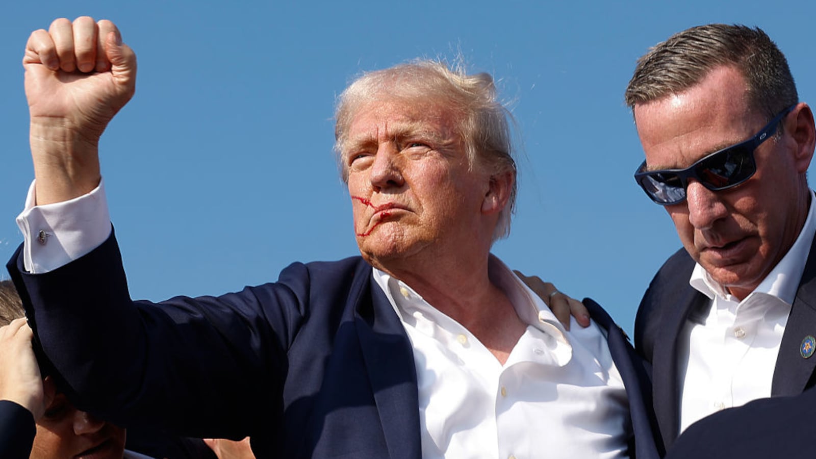 Former President Donald Trump pumps his fist as he is rushed offstage by U.S. Secret Service agents.