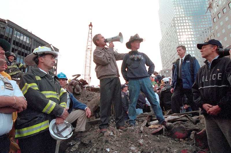 President George W. Bush stands at Ground Zero of the World Trade Center in New York City with retired firefighter Bob Beckwith, addressing approximately 400 police, firemen, and rescue workers.