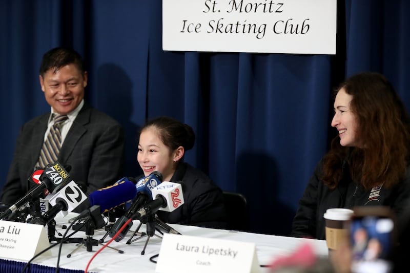Alysa Liu, 13, of Richmond, center, along with her father Arthur Liu, and her coach Laura Lipetsky hold a press conference after practice at Oakland Ice Center