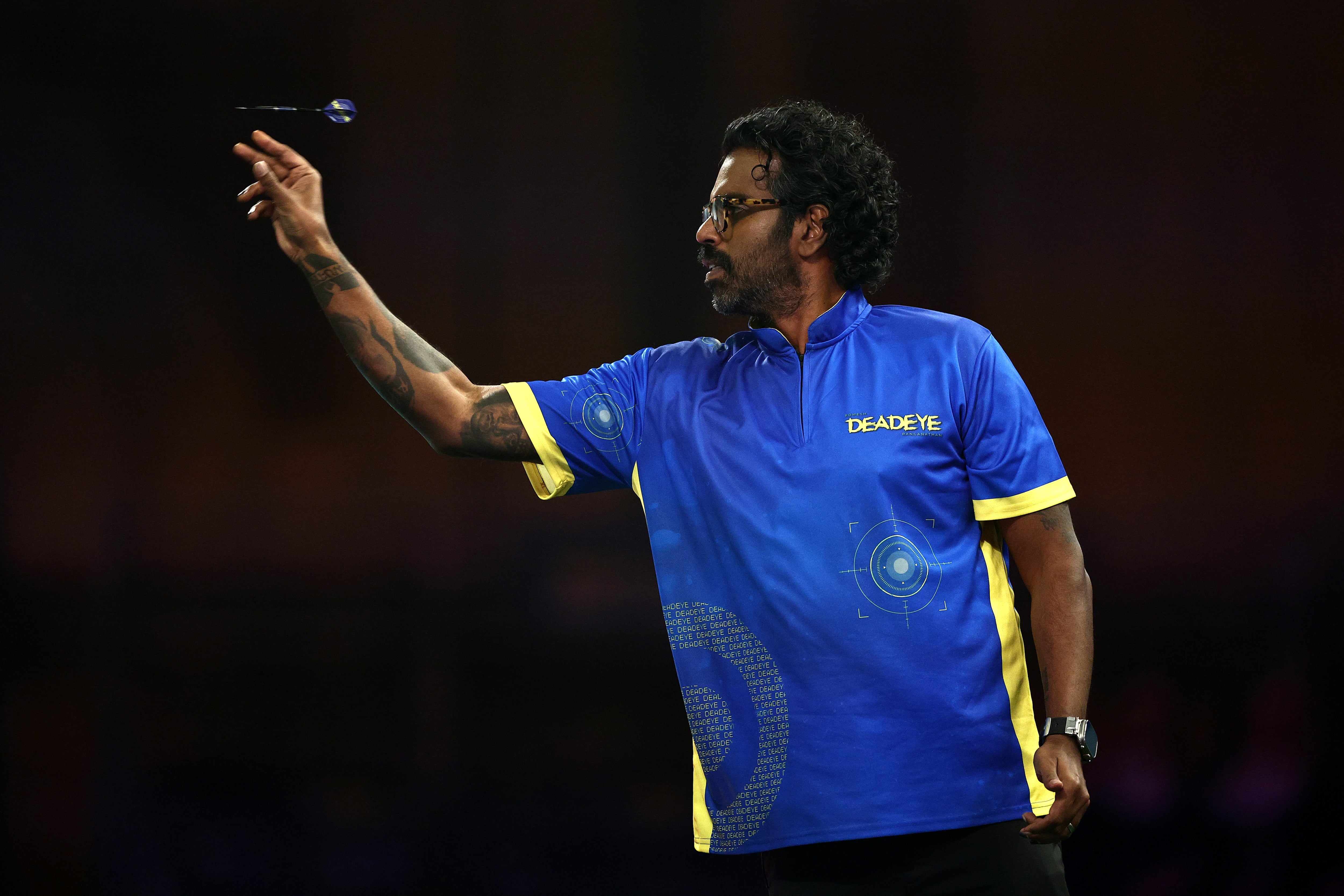 Romesh Ranganathan shows off his tattoo sleeve as he throws a dart during day four of the World Darts Championship in London, England, on December 18, 2024.