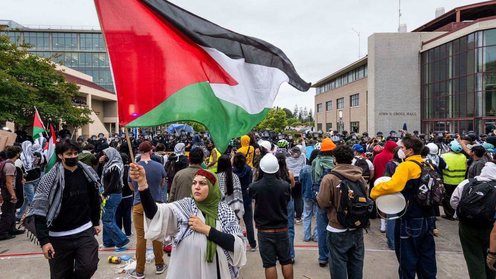 A woman waves the Palestinian flag as police remove a pro-Palestinian encampment at UC Irvine.
