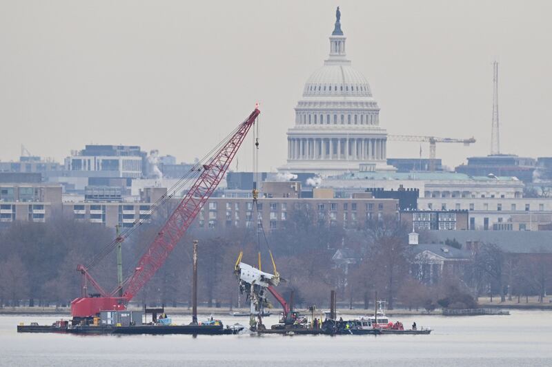 A crane removes airplane wreckage from the Potomac River, where American Airlines flight 5342 collided with a US Army military helicopter, near Ronald Reagan Washington National Airport in Arlington, Virginia.