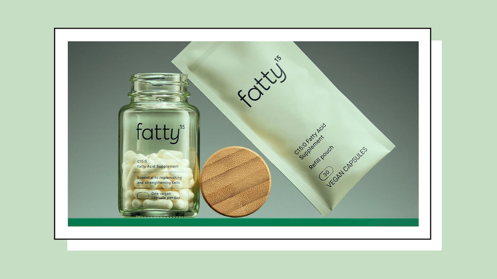 A clear bottle of fatty15 white pills with a wooden cap. There is also a light green bag to the right of the wooden cap.