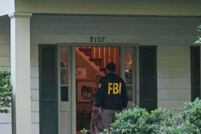 FBI agents speak with tenants at the entrance of John Bolton's house during the morning raid.
