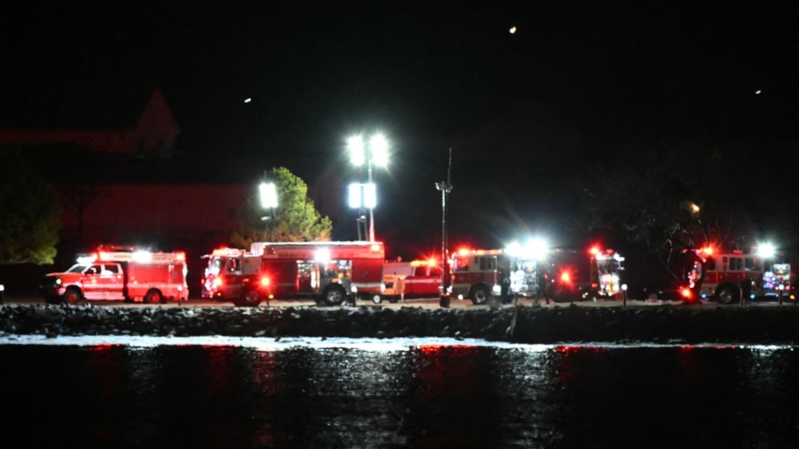 Emergency vehicles and rescue crews gather along the Potomac River.