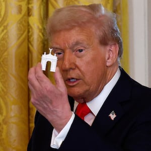 President Donald Trump holds models of an arch as he delivers remarks during a ballroom fundraising dinner in the East Room of the White House on October 15, 2025 in Washington, DC.