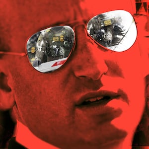 Illo illustration of Stephen Miller with posters of Alex Pretti behind him, all with a red filter, with images of DHS and ICE in Miller's glasses