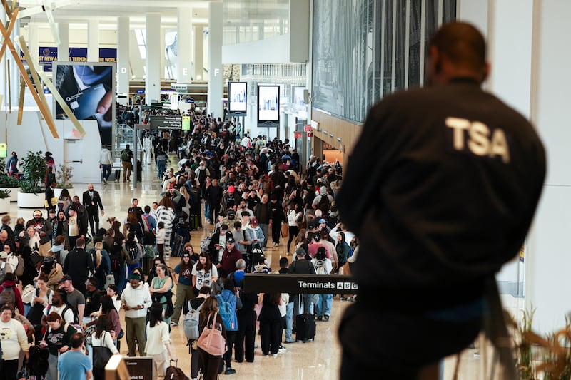 A Transportation Security Administration (TSA) agent looks on passengers queue to go through security at New York's LaGuardia airport on March 22, 2026.