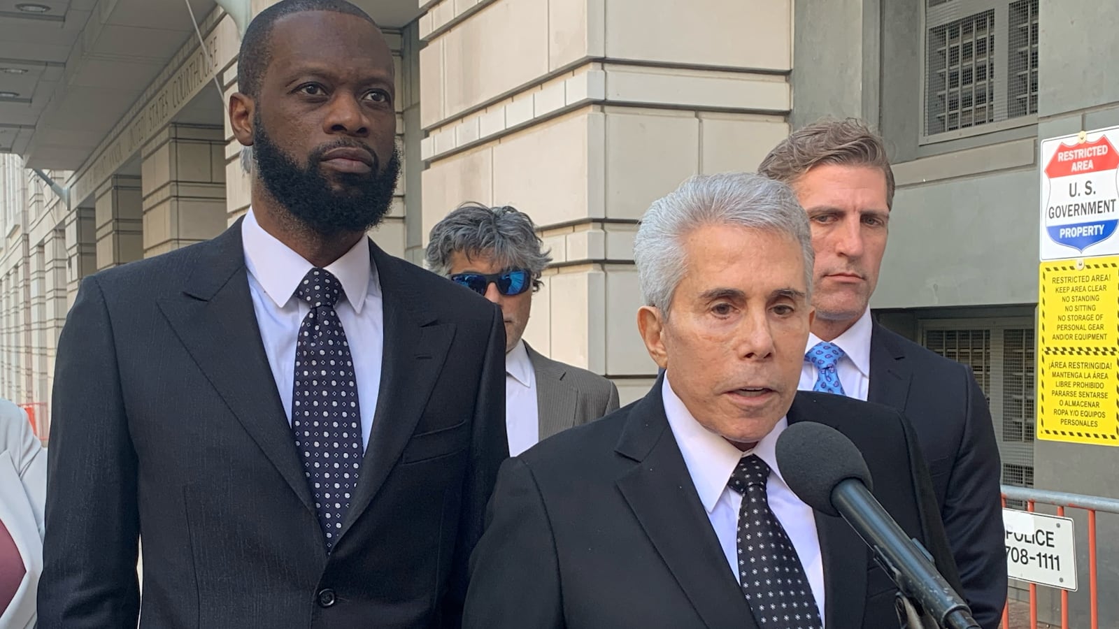 Prakazrel Michel of the hip hop group "The Fugees" listens as his attorney David Kenner talks to reporters outside U.S. federal court.