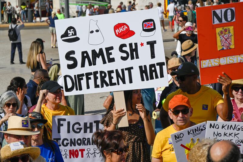 U.S. nationals residing in Portugal hold placards and chant while gathering in Praça do Comercio at a protest organized by American activists living in Portugal, during a "No Kings" protest against U.S. President Donald Trump on October 18, 2025 in Lisbon, Portugal.