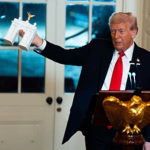 President Donald Trump holds up a model of an arch while delivering remarks during a ballroom fundraising dinner in the East Room of the White House on Wednesday October 15, 2025.
