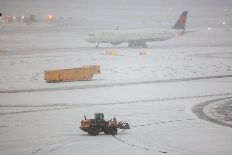 A snow removal machine is seen working while an Airbus A321 Delta Airlines taxied to take off on the tarmac of LaGuardia airport in New York on January 25, 2026. A massive winter storm on January 24, 2026 dumped snow and freezing rain on New Mexico and Texas as it swept across the United States towards the northeast, threatening tens of millions of Americans with blackouts, transportation chaos and bone-chilling cold. Shoppers stripped supermarket shelves as the National Weather Service (NWS) forecast huge snowfall in some areas and possibly "catastrophic" ice accumulations.
