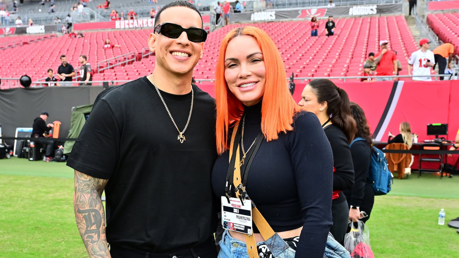 Recording artist Daddy Yankee and his wife Mireddys González pose for a photo on the field before the game between the Tampa Bay Buccaneers and the Carolina Panthers at Raymond James Stadium on January 01, 2023 in Tampa, Florida.